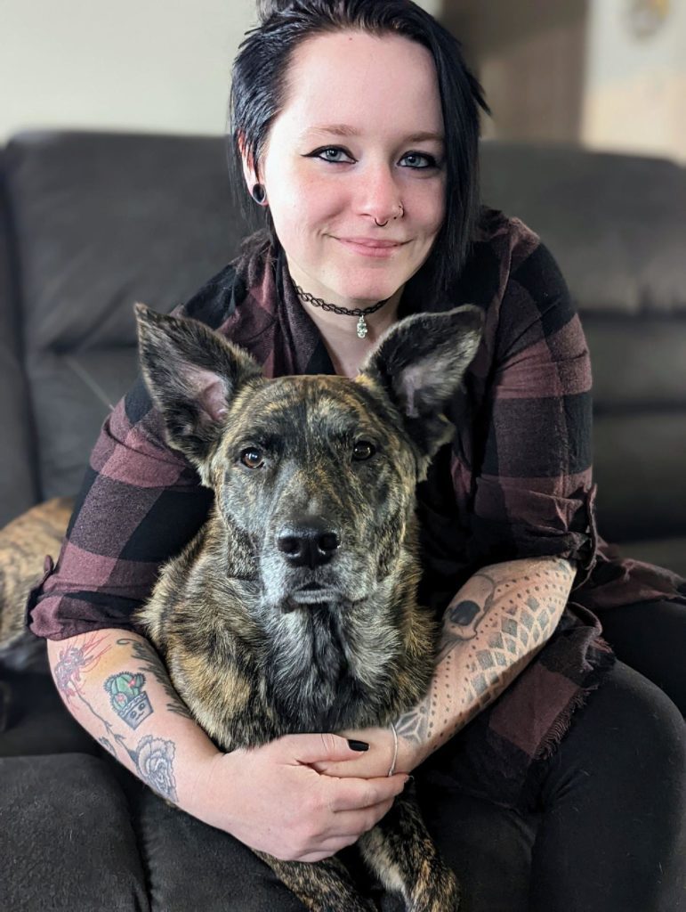 Tattooed woman hugging a dog.