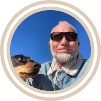 Man wearing sunglasses and taking a photo with a dog